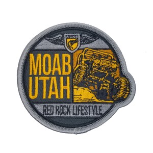 May include: A gray and yellow embroidered patch with a jeep driving through a desert landscape. The text "MOAB UTAH RED ROCK LIFESTYLE" is on the patch.