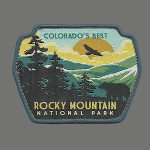 May include: Embroidered patch featuring a scenic mountain landscape with a soaring eagle, a yellow sun, and the text "Colorado's Best Rocky Mountain National Park".