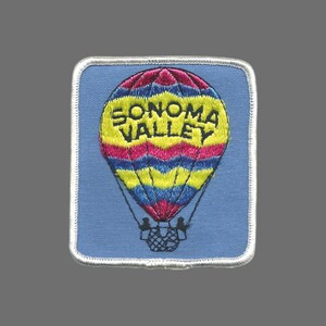 May include: Embroidered patch featuring a colorful hot air balloon with the text "SONOMA VALLEY" in yellow. The balloon has pink, blue, and yellow stripes against a light blue background, with a white border.
