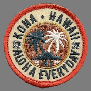 May include: A round, orange-red embroidered patch with a white background. The patch features a palm tree design with the text "Kona Hawaii Aloha Everyday" in black and white.