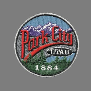 Peut inclure: Patch brodé avec un motif rouge, blanc et bleu. Il représente une chaîne de montagnes, une arche rouge avec le texte "Park City" en blanc, et le texte "UTAH" en blanc à l'intérieur d'un ovale noir. L'année "1884" est en vert sous l'arche.