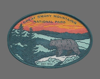 May include: A green, blue, and orange embroidered patch with the text "Great Smoky Mountains National Park" and "Est. 1934". A black bear walks across a mountain range in the background.