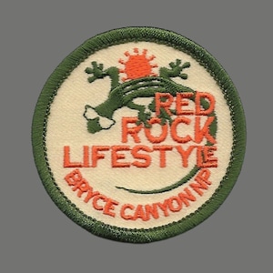 May include: A green and orange embroidered patch with a lizard and the text "Red Rock Lifestyle Bryce Canyon NP".