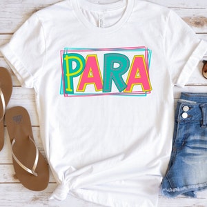 May include: White t-shirt with the word "PARA" in colorful, outlined letters. The letters are pink, yellow, and teal with a stitched effect.