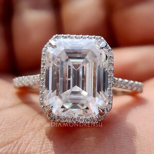 Emerald cut moissanite ring with VVS clarity, set in a 14k white gold band with a sparkling halo, viewed from above showing the clear facets