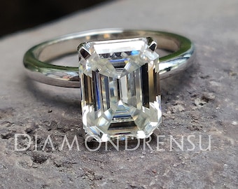 May include: A silver ring with a large, clear emerald-cut diamond.