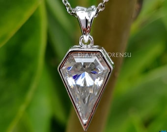 May include: A silver pendant necklace with a large, clear, diamond-shaped gemstone set in a geometric frame. The pendant is hanging from a silver chain.