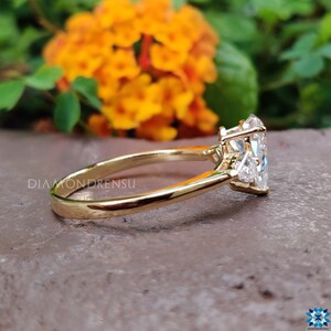 May include: A gold engagement ring with a large, clear, heart-shaped diamond and two smaller diamonds on the band.
