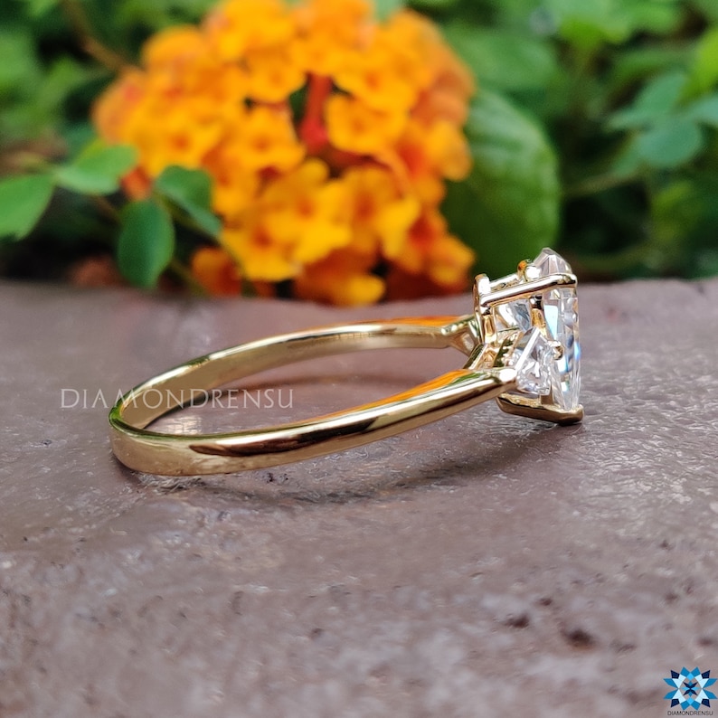May include: A gold engagement ring with a large, clear, heart-shaped diamond and two smaller diamonds on the band.
