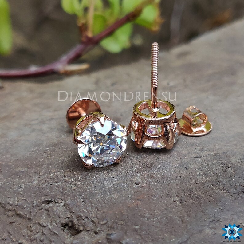 Pode incluir: Um par de brincos de press&atilde;o de ouro rosa com uma pedra redonda transparente no centro. Os brincos t&ecirc;m um fecho de rosca.
