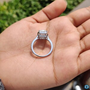 Emerald cut halo ring placed casually on a marble surface, invoking a lifestyle of elegance and the timeless beauty of the design