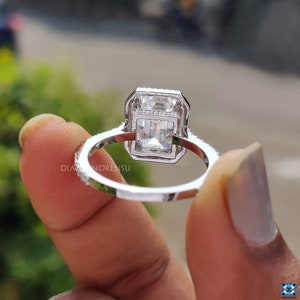 Emerald cut halo engagement ring on a finger, displaying how the ring complements the hand with its elegant 14k white gold band