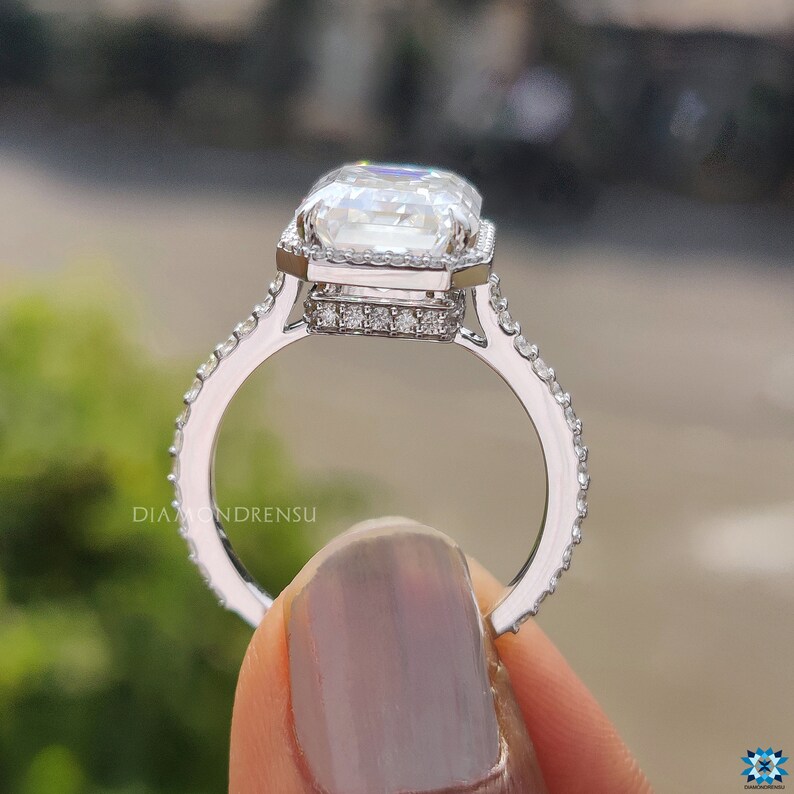 Side view of a white gold moissanite ring, highlighting the emerald cut stone and the hidden halo detail beneath the setting