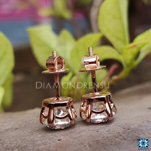 Pode incluir: Um par de brincos de press&atilde;o de ouro rosa com uma gema redonda e transparente em cada engaste. Os brincos t&ecirc;m um fecho de rosca.