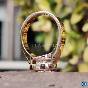 Op de afbeelding: Een verlovingsring van ros&eacute;goud met een grote, heldere, ronde diamant in een bezel-setting. De ring heeft een dikke band met een licht gebogen ontwerp.