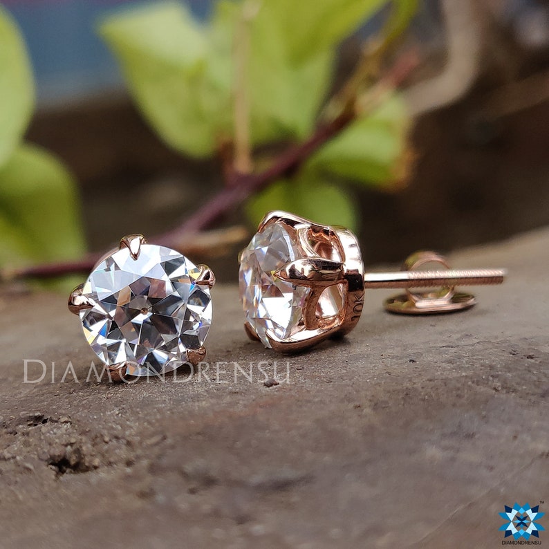Pode incluir: Um par de brincos de press&atilde;o de ouro rosa com pedras de moissanita redondas e transparentes engastadas em garras.