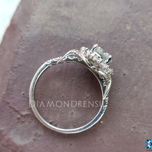 May include: A silver engagement ring featuring a large, square-cut diamond centre stone encircled by a halo of smaller diamonds. The ring has a delicate, intricate design with a twisted band.