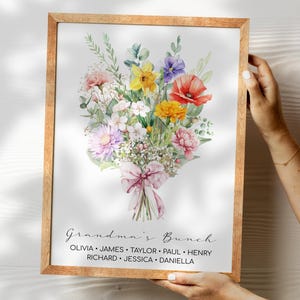 May include: A watercolor print of a bouquet of flowers in a wooden frame. The flowers are in shades of pink, yellow, red, and purple. The text "Grandma's Bunch" is printed below the flowers, followed by a list of names: Olivia, James, Taylor, Paul, Henry, Richard, Jessica, and Daniella.