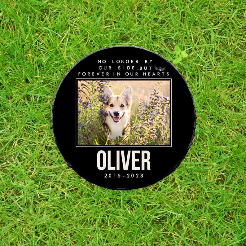 May include: Black memorial stone with a photo of a dog, the text "No longer by our side, but forever in our hearts", the dog's name "Oliver", and the dates "2015-2023".