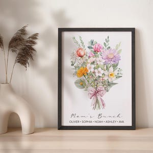 May include: A framed watercolor print of a bouquet of flowers in shades of pink, yellow, and white. The flowers are tied with a pink ribbon and the text "Mom's Brunch" is printed below the bouquet. The names "Oliver, Sophia, Noah, Ashley, Ava" are printed below the text.