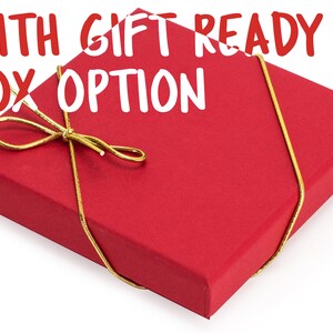 May include: A red gift box with a gold ribbon tied in a bow. The box is ready for gift giving and has the text "WITH GIFT READY BOX OPTION" printed on the top.