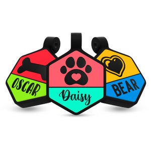 May include: Three colorful hexagonal dog tags with black outlines. The top tag is yellow with a blue bottom and says "BEAR". The middle tag is pink with a turquoise bottom and says "Daisy". The bottom tag is red with a green bottom and says "OSCAR".