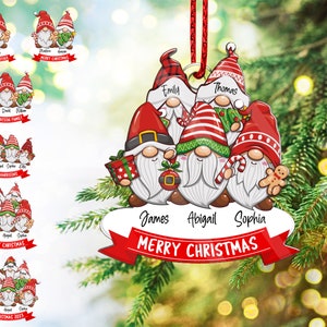 May include: A red and white Christmas ornament featuring five gnomes with different hats and beards. The gnomes are holding gifts, candy canes, and a gingerbread man. The ornament has the text "Merry Christmas" on a red ribbon.