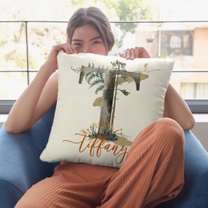 May include: A white throw pillow with a watercolor design of a tree and ferns. The letter "T" is incorporated into the design, and the name "Tiffany" is written in cursive at the bottom.