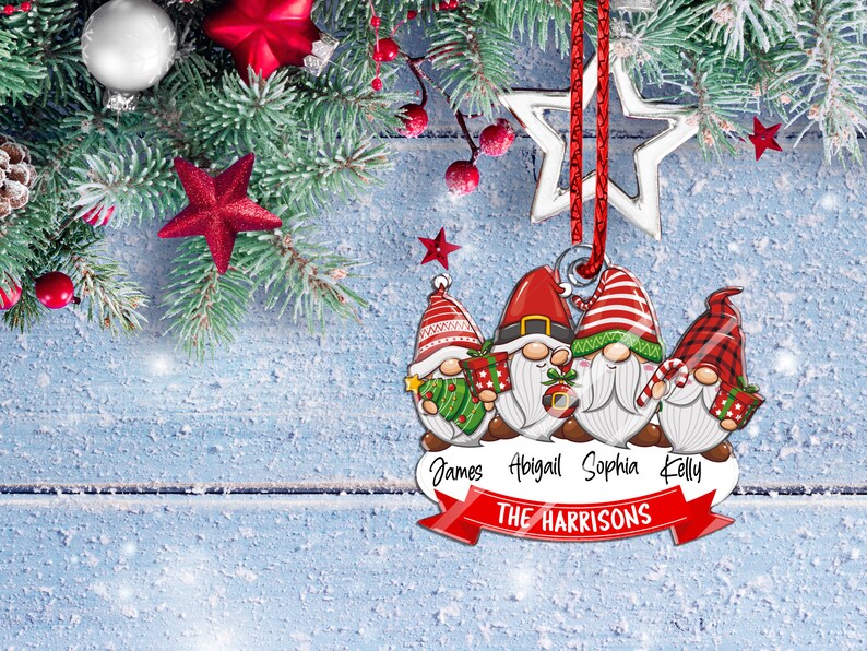 May include: A Christmas ornament featuring four gnomes with red hats and white beards. Each gnome is holding a gift and the ornament has the names "James, Abigail, Sophia, Kelly" and "THE HARRISONS" written on it.