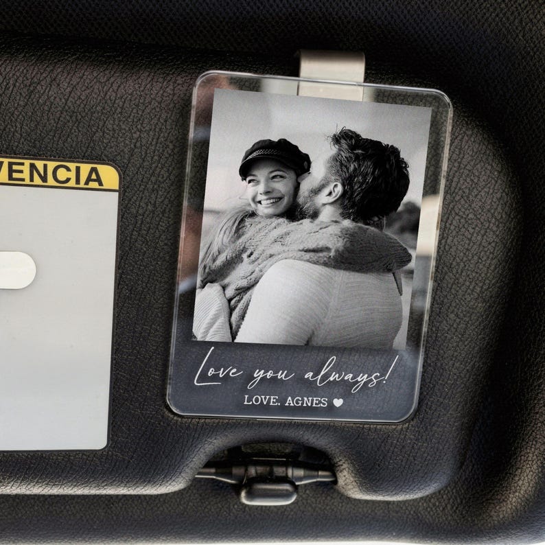 May include: Clear acrylic visor clip featuring a black and white photo of a person embracing another person. The text "Love you always!" and "LOVE, AGNES" is printed on the bottom.