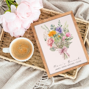 May include: A framed print with a watercolor illustration of a bouquet of flowers in shades of pink, purple, yellow, and white. The bouquet is tied with a pink ribbon and the text "Mom's Brunch" is written below the flowers. The names "James, Sofia, Michael, Olivia" are written below the text.