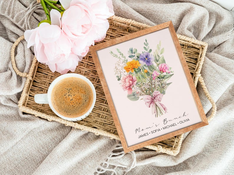May include: A framed print with a watercolor illustration of a bouquet of flowers in shades of pink, purple, yellow, and white. The bouquet is tied with a pink ribbon and the text "Mom's Brunch" is written below the flowers. The names "James, Sofia, Michael, Olivia" are written below the text.