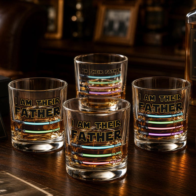 May include: Four clear whiskey glasses with the text "I AM THEIR FATHER" in black. Each glass has a colorful, horizontal light saber design with names. The glasses are filled with amber liquid, likely whiskey.