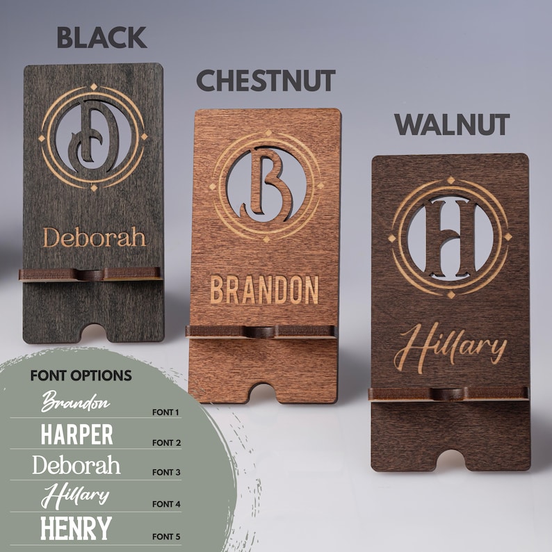 May include: Wooden phone stands in black, chestnut, and walnut. Each stand features a personalized name and initial within a decorative circle. Font options are displayed below the stands.