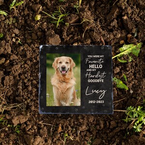 May include: Black slate memorial stone with a photo of a golden retriever dog. The text reads "You were my favourite hello and my hardest goodbye Lucy 2012-2023".