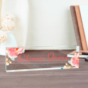 May include: A clear acrylic desk nameplate with a floral design and the text "Olivia Davis, Architect".