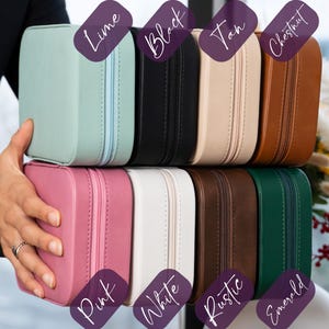 K&ouml;nnte beinhalten: Eine Auswahl an quadratischen Schmuckk&auml;stchen mit Rei&szlig;verschluss in verschiedenen Farben: Limette, Schwarz, Beige, Kastanie, Rosa, Wei&szlig;, Rustikal und Smaragdgr&uuml;n. Eine Person h&auml;lt die K&auml;stchen, um die Farbpalette zu zeigen.