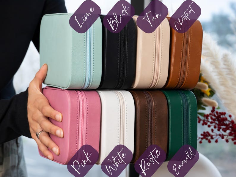 K&ouml;nnte beinhalten: Eine Auswahl an quadratischen Schmuckk&auml;stchen mit Rei&szlig;verschluss in verschiedenen Farben: Limette, Schwarz, Beige, Kastanie, Rosa, Wei&szlig;, Rustikal und Smaragdgr&uuml;n. Eine Person h&auml;lt die K&auml;stchen, um die Farbpalette zu zeigen.