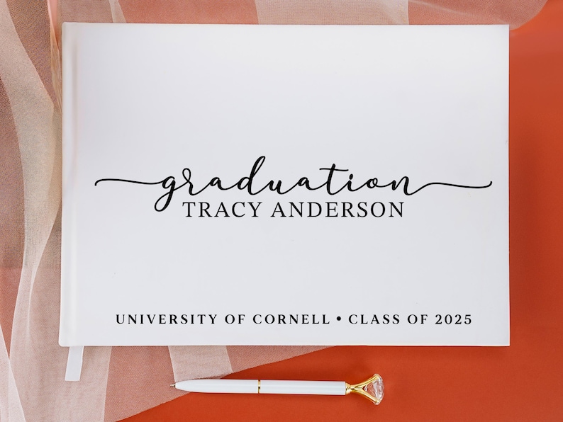May include: White graduation guest book with the text "graduation TRACY ANDERSON UNIVERSITY OF CORNELL CLASS OF 2025" printed on the front.