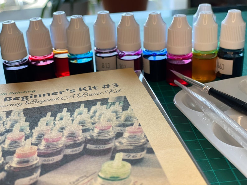 May include: A beginner's silk painting kit with 10 bottles of dye in various colors, a paintbrush, and a palette. The kit includes a guide titled "Beginner's Kit #3 Journey Beyond A Basic Kit".