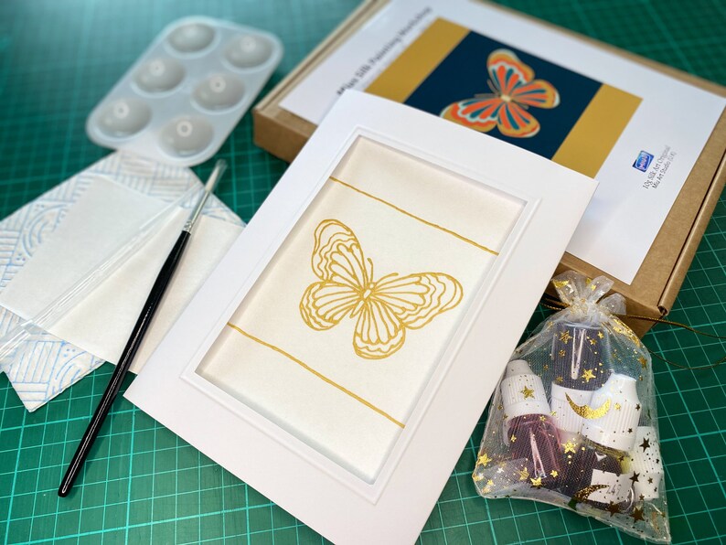 May include: A gold butterfly painting kit with a white frame, a paintbrush, a palette, and a bag of paint.