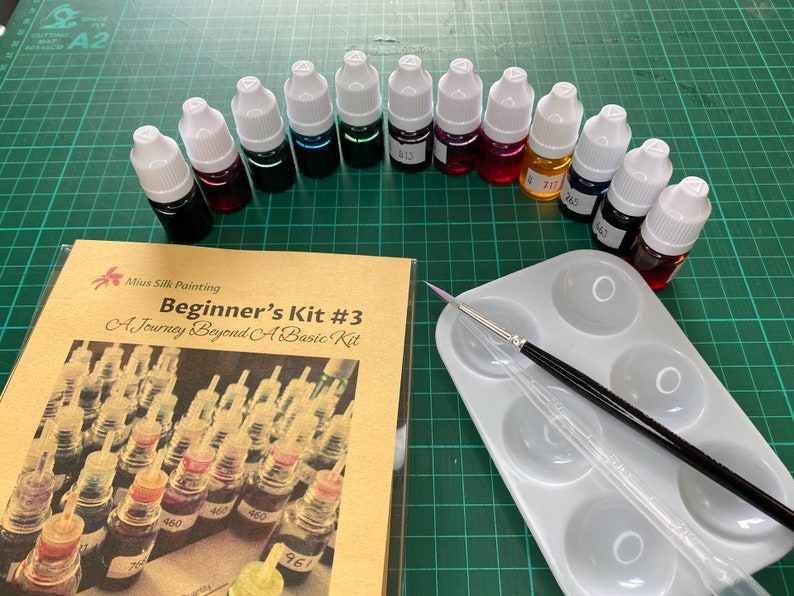 May include: A beginner's silk painting kit with 12 bottles of dye in various colors, a small paint palette, and a paintbrush. The kit includes a guidebook titled "Beginner's Kit #3: A Journey Beyond A Basic Kit".