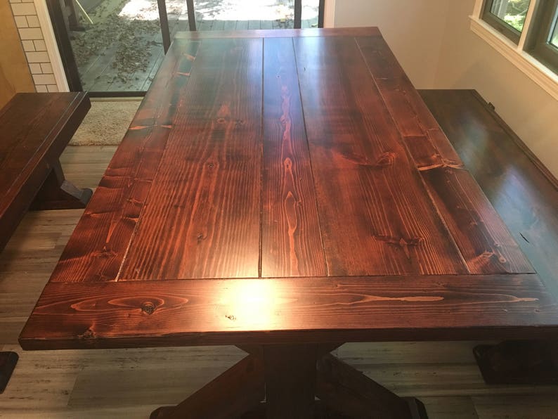 May include: A large, dark wood dining table with a rectangular top and a thick, sturdy base. The table has a rich, dark brown finish and a smooth, polished surface.