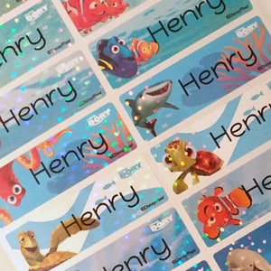 May include: A set of 10 colourful, iridescent, rectangular stickers with the name "Henry" printed on each one. The stickers feature various characters from the Disney Pixar movie Finding Dory, including Dory, Nemo, Marlin, and Crush the turtle.