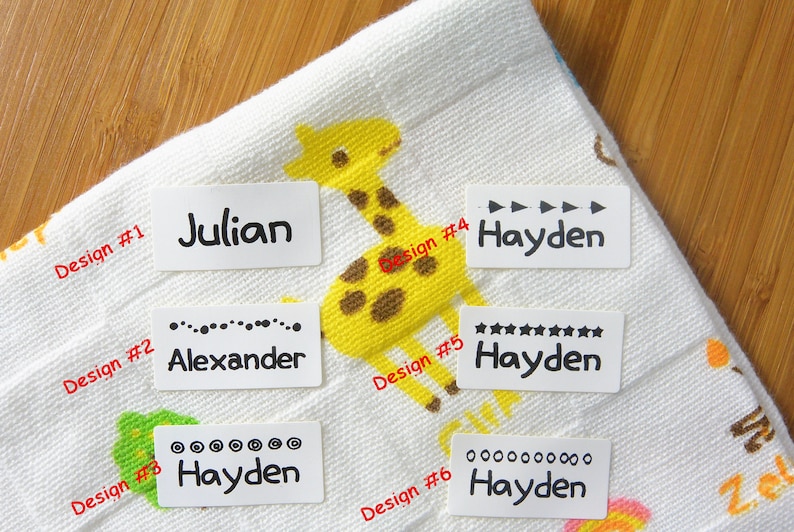 May include: Six white rectangular iron-on labels with different designs and names printed in black. The names are Julian, Alexander, Hayden, Hayden, Hayden, and Hayden. The designs include a line of dots, stars, circles, and arrows.