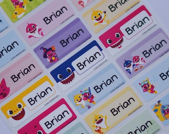 May include: A sheet of colorful labels with the name "Brian" printed on each one. The labels feature various cartoon images of baby sharks in different colors and poses.