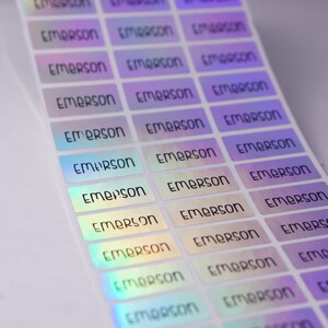 May include: A sheet of iridescent holographic stickers with the name "Emerson" printed on each sticker.