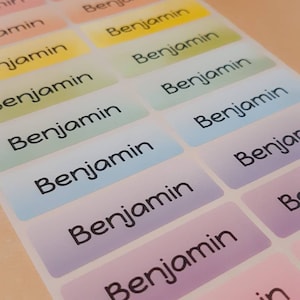 May include: A set of colourful labels with the name "Benjamin" printed on them. The labels are arranged in a row, with each label having a different colour gradient.