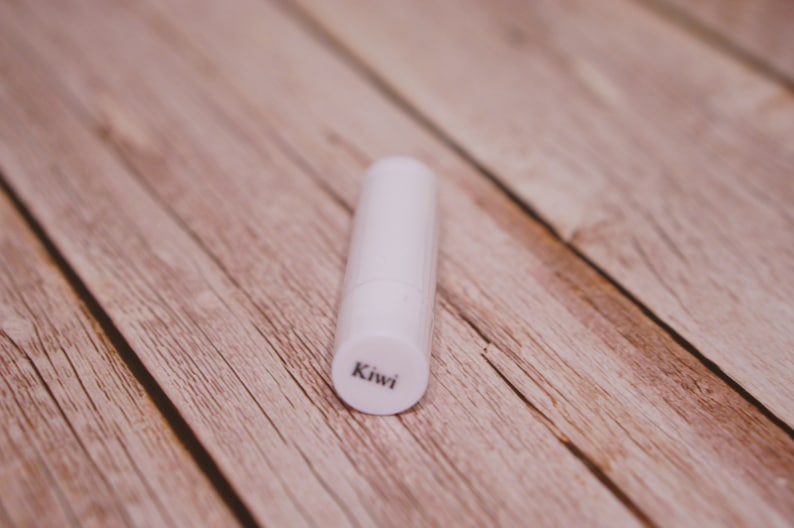 May include: A white lip balm tube with the word "Kiwi" printed on the bottom.