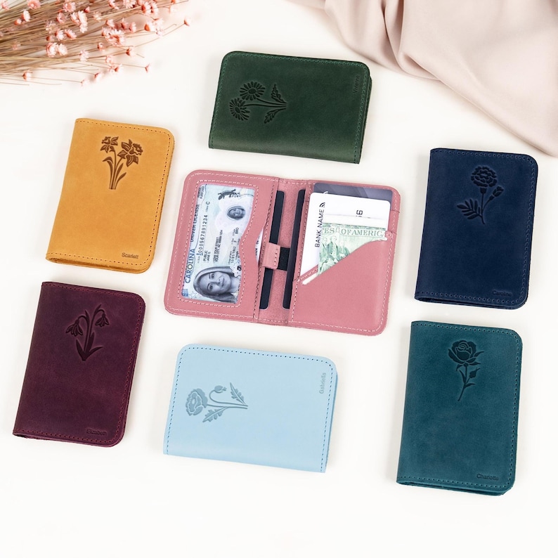 May include: A collection of leather wallets in various colors, including mustard yellow, deep burgundy, and teal. Each wallet features an embossed floral design. One wallet is open, displaying a driver's license and credit cards.